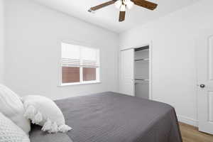Bedroom featuring ceiling fan, visible vents, wood finished floors, baseboards, and a closet
