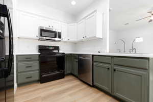 Kitchen featuring white cabinets, light wood-style flooring, a sink, and black appliances