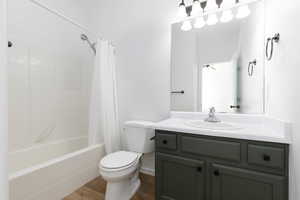 Full bathroom with vanity, toilet, wood finished floors, and shower / tub combo