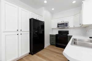Kitchen featuring a sink, light countertops, black appliances, and light wood-type flooring