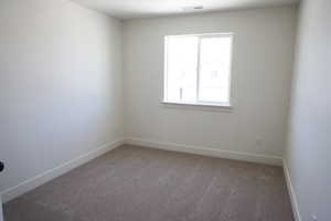 Carpeted empty room with visible vents and baseboards