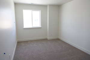 Carpeted spare room with visible vents and baseboards