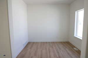 Empty room featuring visible vents, light wood-style flooring, and baseboards