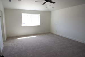 Carpeted empty room with baseboards, a ceiling fan, and visible vents