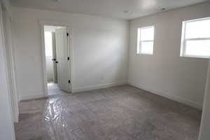 Empty room featuring baseboards, visible vents, and light colored carpet