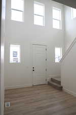 Entrance foyer with a high ceiling, visible vents, wood finished floors, and stairway