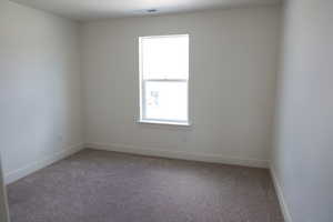 Carpeted spare room featuring baseboards and visible vents