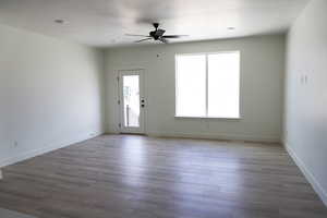 Unfurnished living room with baseboards, a ceiling fan, and wood finished floors
