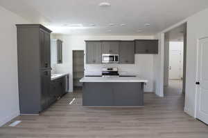 Kitchen featuring light countertops, baseboards, a kitchen island, and stainless steel appliances
