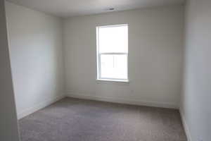 Empty room with baseboards, visible vents, and carpet