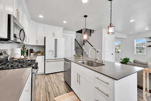 Kitchen with a sink, stainless steel appliances, open floor plan, recessed lighting, and white cabinetry
