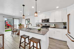 Kitchen featuring decorative backsplash, dark countertops, recessed lighting, a sink, and appliances with stainless steel finishes