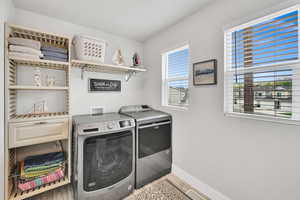 Washroom with baseboards, laundry area, washing machine and dryer, and light wood finished floors