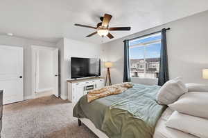 Carpeted bedroom featuring baseboards, a ceiling fan, and a textured ceiling