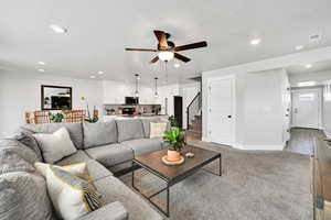 Living area with recessed lighting, ceiling fan, visible vents, and stairway