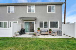 Back of property featuring fence, outdoor lounge area, cooling unit, a lawn, and a patio