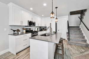 Kitchen with dark countertops, tasteful backsplash, a sink, baseboards, and stainless steel appliances