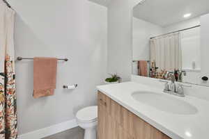 Full bath with baseboards, tile patterned floors, toilet, and vanity