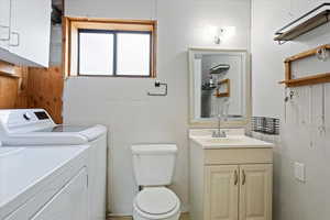 Bathroom featuring toilet, washer and clothes dryer, and vanity