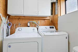 Clothes washing area with laundry area, wooden walls, and washer and dryer