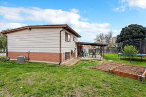View of home's exterior with a trampoline, brick siding, a fenced backyard, a patio area, and a lawn