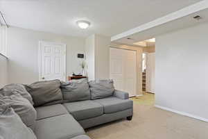 Living room featuring visible vents, baseboards, light colored carpet, and stairway