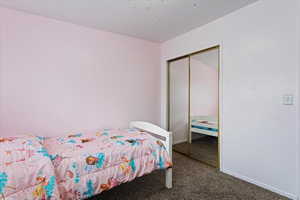Bedroom with carpet floors, baseboards, and a closet