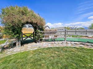 Archway with greenery leading to fenced backyard water feature area