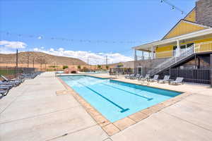 Community pool with stairway, fence, a mountain view, and a patio area