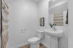 Half bath featuring toilet, baseboards, and wood finished floors