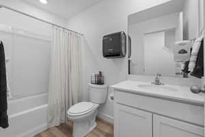 Full bathroom featuring toilet, shower / bath combo with shower curtain, wood finished floors, and vanity