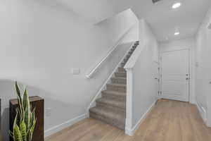 Staircase featuring baseboards, recessed lighting, wood finished floors, and visible vents