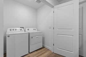 Laundry area with laundry area, visible vents, washing machine and dryer, baseboards, and light wood finished floors
