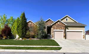 Craftsman-style house featuring stucco siding, concrete driveway, a front yard, and stone siding