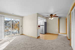 Unfurnished living room with light carpet and ceiling fan