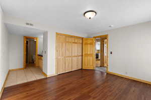 Unfurnished bedroom featuring wood finished floors, a closet, a textured ceiling, and connected bathroom