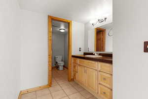 Bathroom featuring a textured ceiling, light tile patterned floors, and vanity