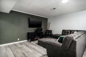 Downstairs Living room with visible vents, baseboards, and wood finished floors