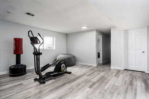 Exercise room with baseboards, wood finished floors, and visible vents