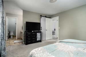 View of Master Bedroom Bathroom, barn door into the walk-in closet, and carpet flooring