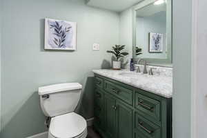 Downstairs Bathroom featuring vanity, baseboards, shower / tub combination, and toilet