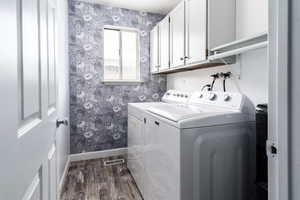 Laundry area with washing machine and clothes dryer, cabinet space, baseboards, wallpapered walls, and LVP floors