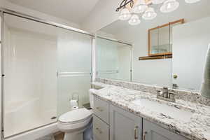 Full bathroom featuring vanity, toilet, an inviting chandelier, and a stall shower