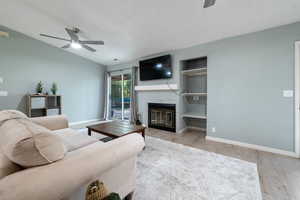 Living area featuring baseboards, a ceiling fan, a textured ceiling, and wood finished floors