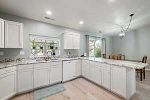 Kitchen with a peninsula, light wood-type flooring, a sink, and dishwasher