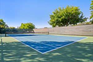 View of tennis court with fence and community basketball court