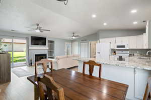 Dining area with a textured ceiling, ceiling fan, and visible vents