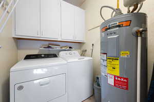 Clothes washing area with separate washer and dryer, cabinet space, and electric water heater
