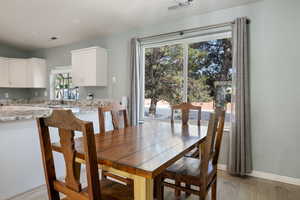 Dining space with baseboards, visible vents, and light wood finished floors