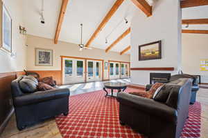 Living room featuring a glass covered fireplace, track lighting, french doors, and beam ceiling